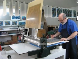 Patrick Simon operating the printing press in his studio.
